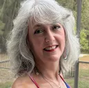 Dr. Ellen Mosti smiling in a colorful sleeveless top with shoulder-length silver hair.