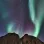rocks against a night sky with green and purple northern lights