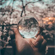 hand holding crystal ball reflecting an outdoor scene