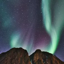 rocks against a night sky with green and purple northern lights