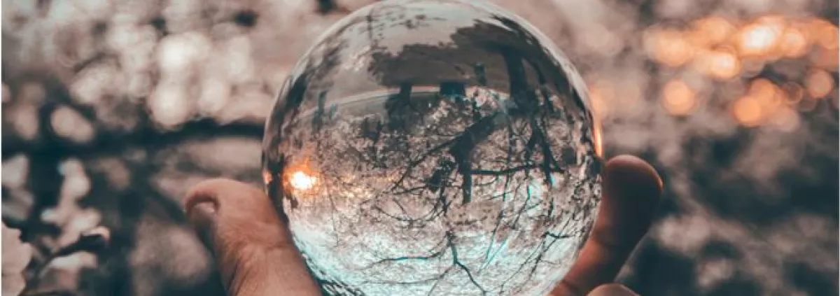 hand holding crystal ball reflecting an outdoor scene