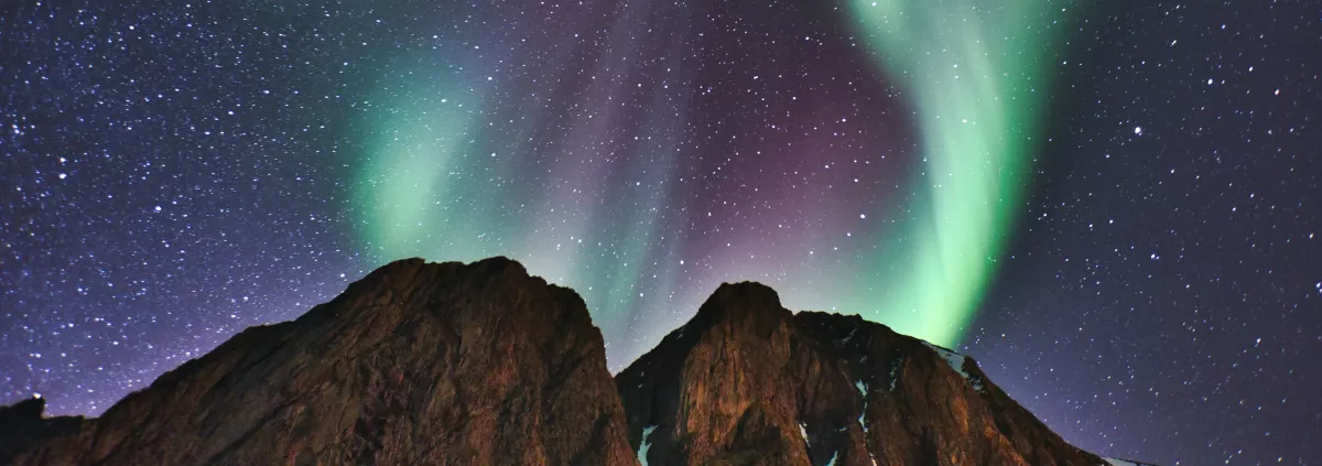 rocks against a night sky with green and purple northern lights