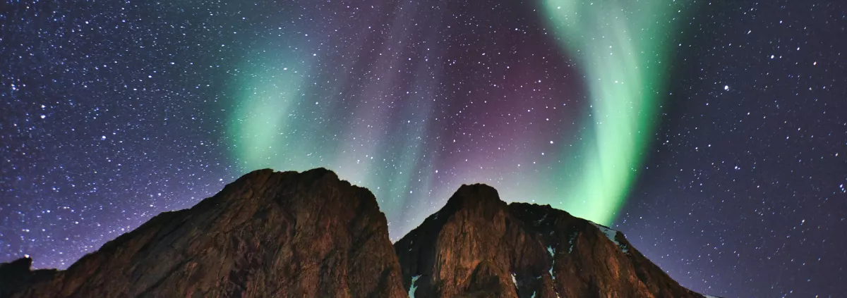mountains against a night sky with green and purple northern lights